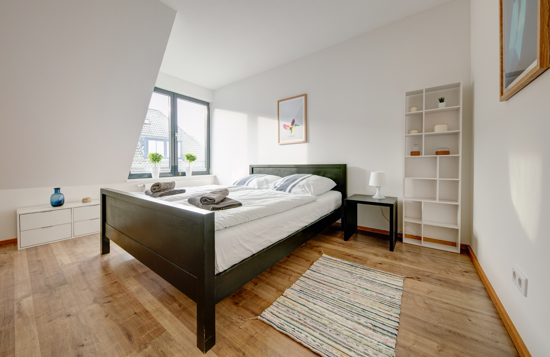 Schlafzimmer mit dunklem Bett in heller Ferienwohnung Seestern