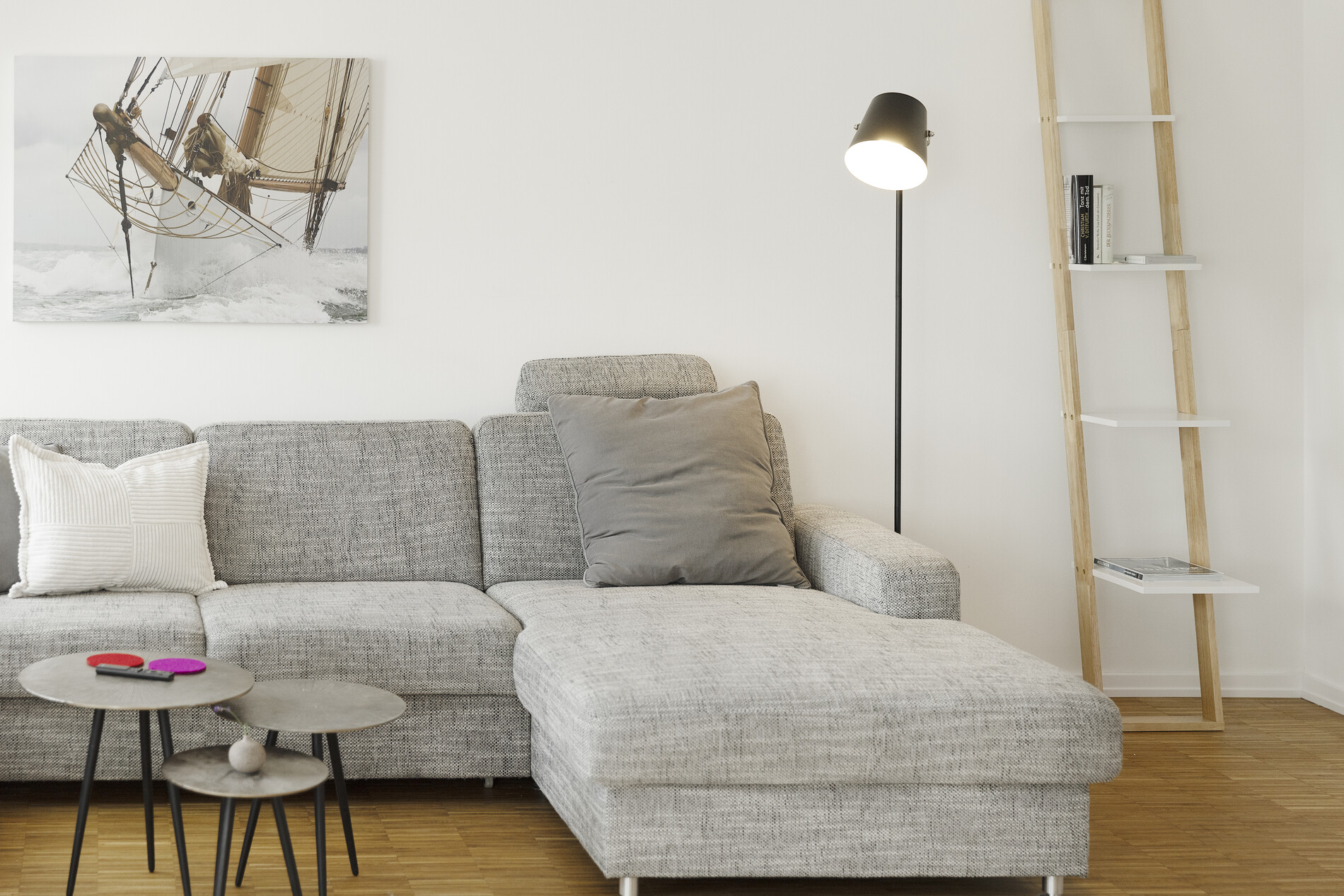Graues Sofa, Stehlampe und schmales Bücherregal